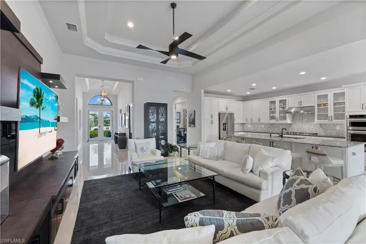 Living room with french doors, ceiling fan, a raised ceiling, and tile patterned flooring