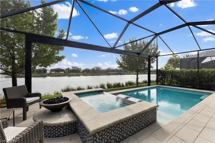 View of pool featuring a patio area, an in ground hot tub, a water view, and picture window screen  enclosure