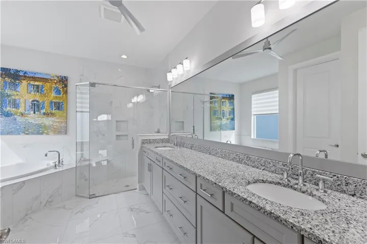 Bathroom featuring plus walk in shower, tile patterned floors, ceiling fan, and dual bowl vanity