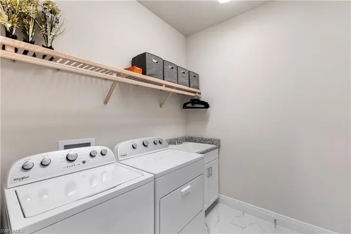 Laundry area featuring cabinets, washing machine and clothes dryer, sink, and light tile patterned floors