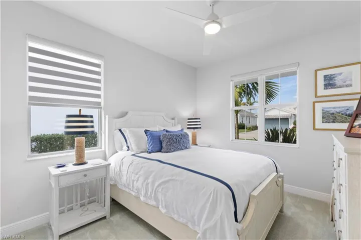 Bedroom featuring light carpet, multiple windows, and ceiling fan