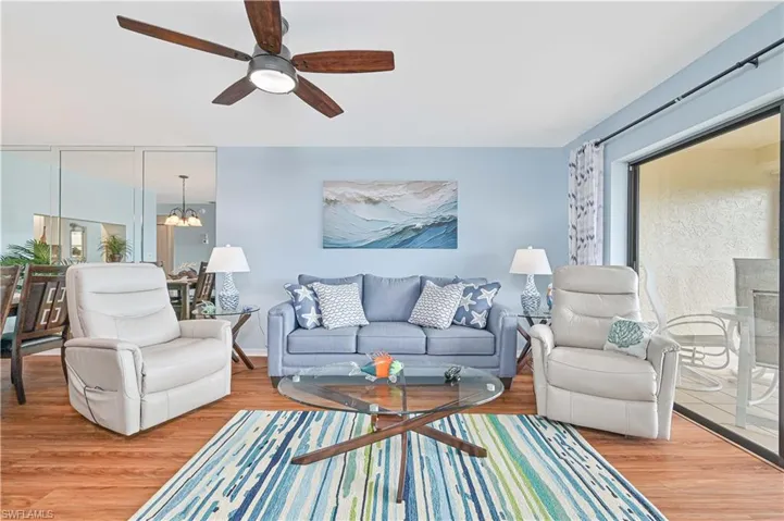Living area featuring a chandelier, wood finished floors, a ceiling fan, and healthy amount of natural light
