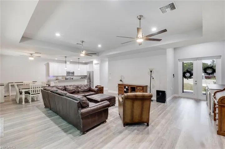 Living room featuring light hardwood / wood-style floors, ceiling fan, and a tray ceiling