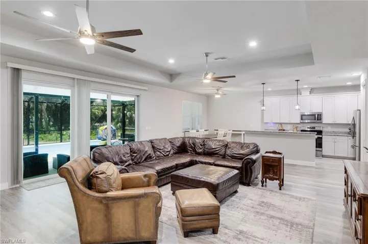 Living room featuring ceiling fan, light hardwood / wood-style floors, and a tray ceiling