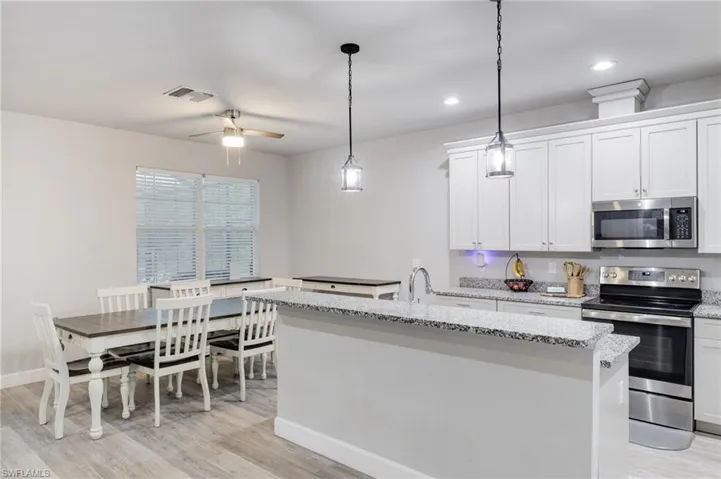 Kitchen featuring appliances with stainless steel finishes, white cabinets, light wood-type flooring, and ceiling fan