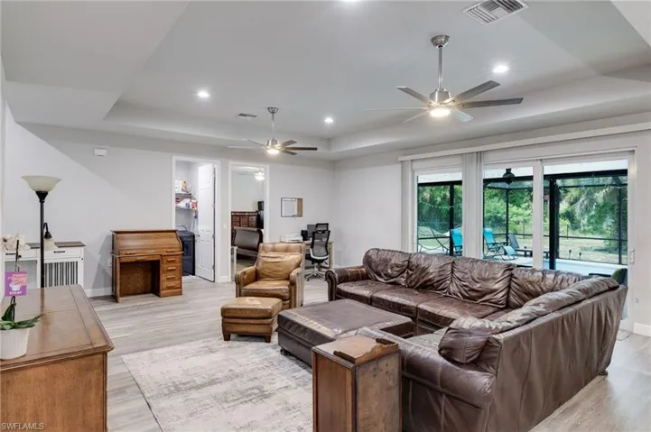 Living room with light wood-type flooring, a tray ceiling, and ceiling fan