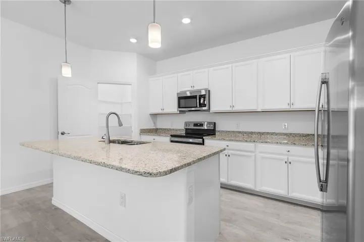 Kitchen with large island, walk in pantry, stainless steel appliances, white cabinets