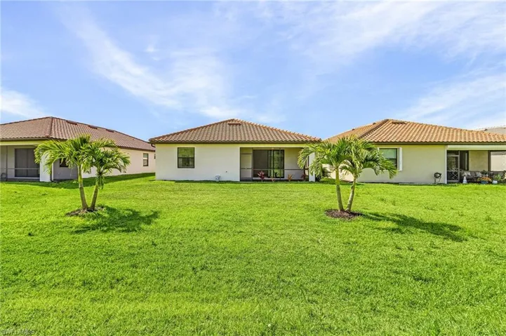 Back of house featuring stucco siding, a yard, and a tile roof