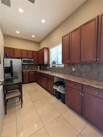 Kitchen featuring appliances with stainless steel finishes, dark stone counters, recessed lighting, light tile patterned floors, and decorative backsplash