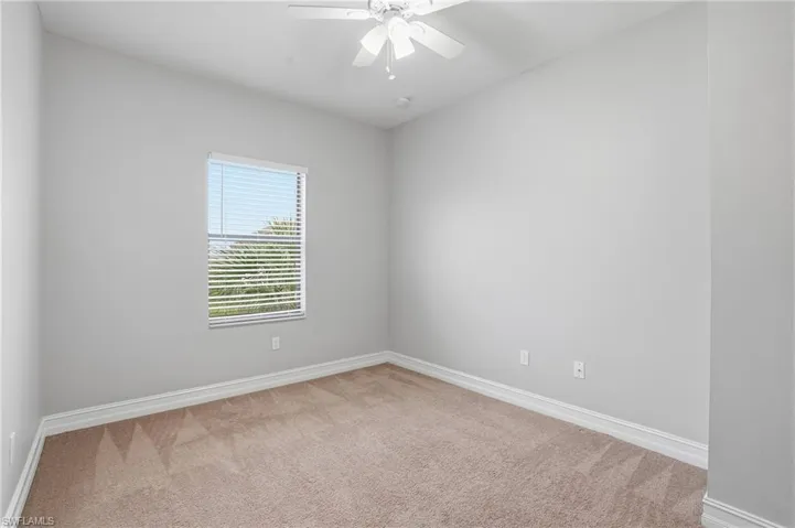 Empty room with light colored carpet and a ceiling fan
