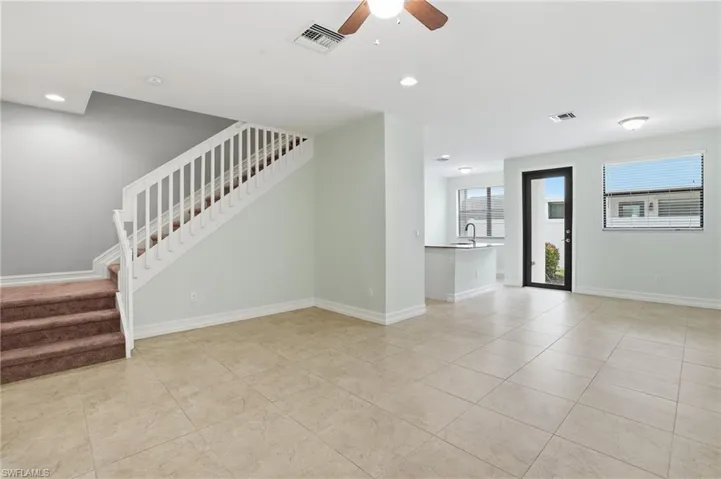 Unfurnished living room featuring stairway, a ceiling fan, light tile patterned floors, and recessed lighting