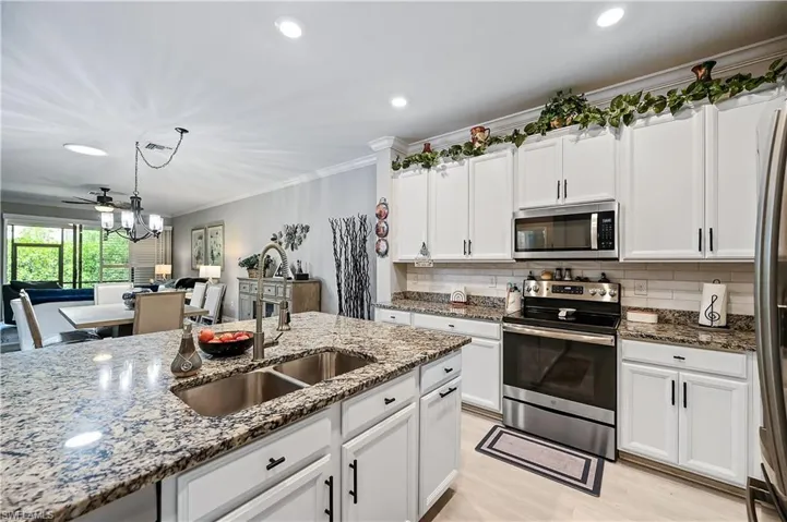 Kitchen with tasteful backsplash, light stone countertops, appliances with stainless steel finishes, sink, and pendant lighting