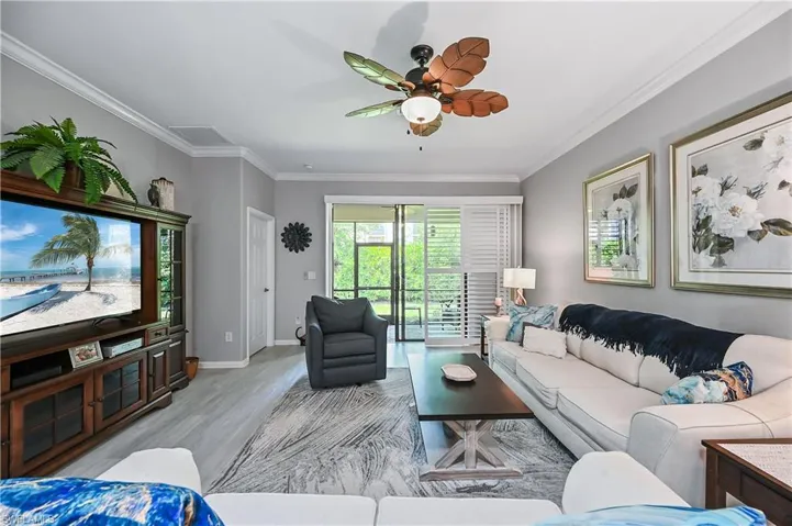 Living room featuring wood-type flooring, ornamental molding, and ceiling fan