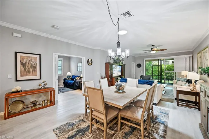 Dining area with ceiling fan with notable chandelier, light hardwood / wood-style flooring, and crown molding