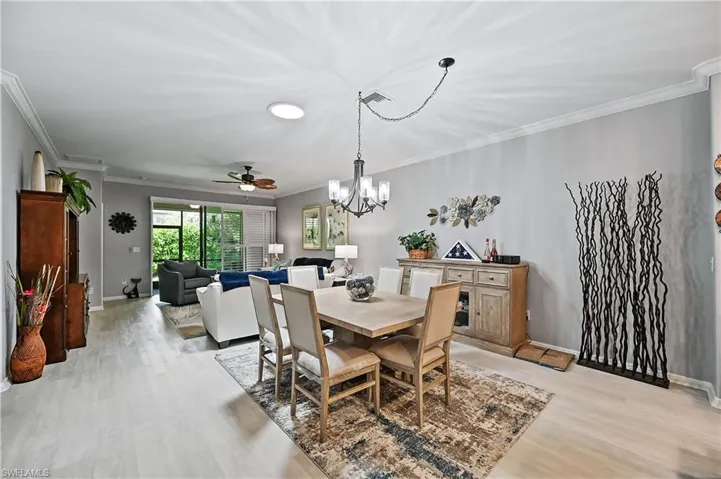 Dining space featuring ceiling fan with notable chandelier, light hardwood / wood-style flooring, and crown molding