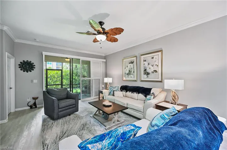 Living room with wood-type flooring, ceiling fan, and crown molding
