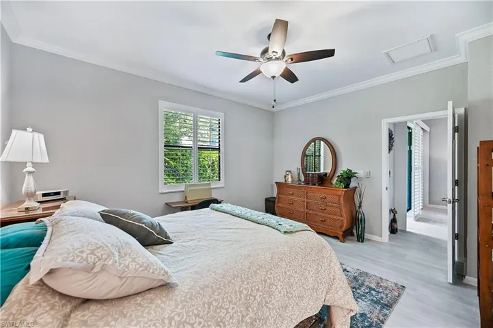Bedroom with hardwood / wood-style flooring, ceiling fan, and ornamental molding