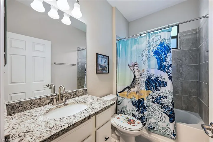 Full bathroom featuring large vanity, toilet, and shower / tub combo with curtain