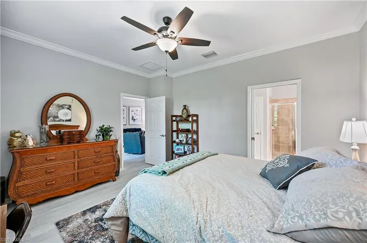 Bedroom featuring ceiling fan, crown molding, and connected bathroom