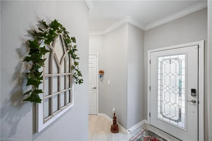 Foyer with ornamental molding and light wood-type flooring
