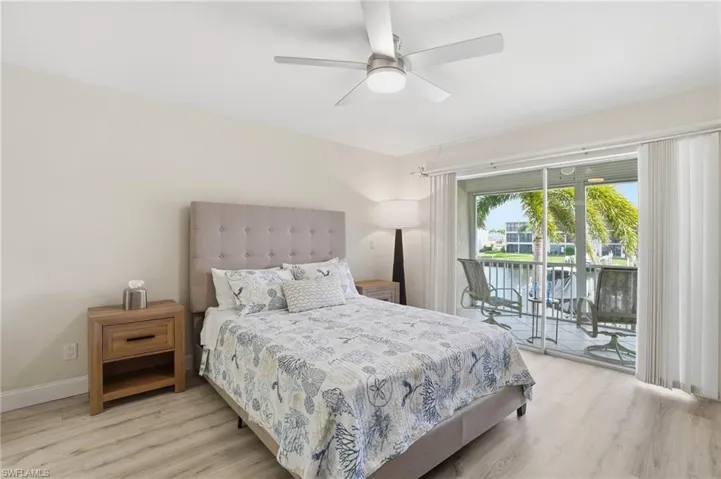 Bedroom featuring a water view, light wood-style floors, access to outside, and a ceiling fan