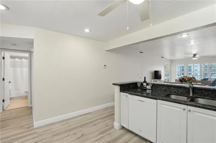 Kitchen featuring white cabinetry, ceiling fan, dark stone counters, dishwasher, and light LVP  flooring