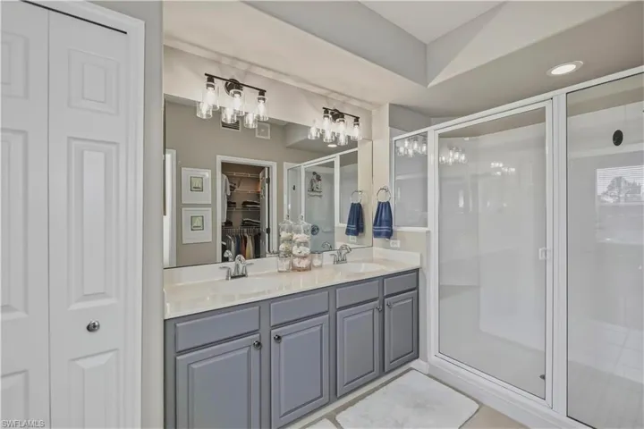 Dual vanity with gray cabinetry, a light-toned countertop, and two framed mirrors