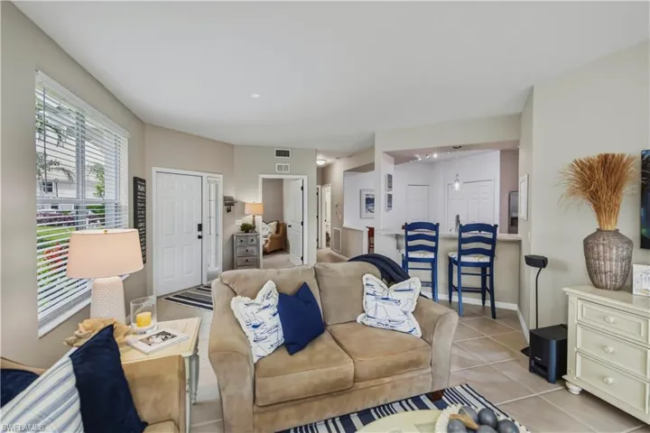 Spacious living area featuring neutral wall tones, tile flooring, and a large window with horizontal blinds