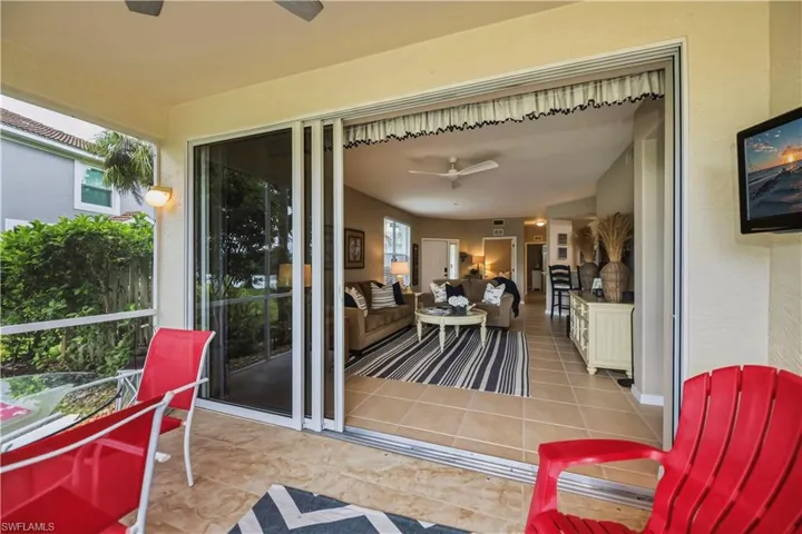 Screened lanai featuring tile flooring, wall-mounted light fixtures, and a ceiling fan