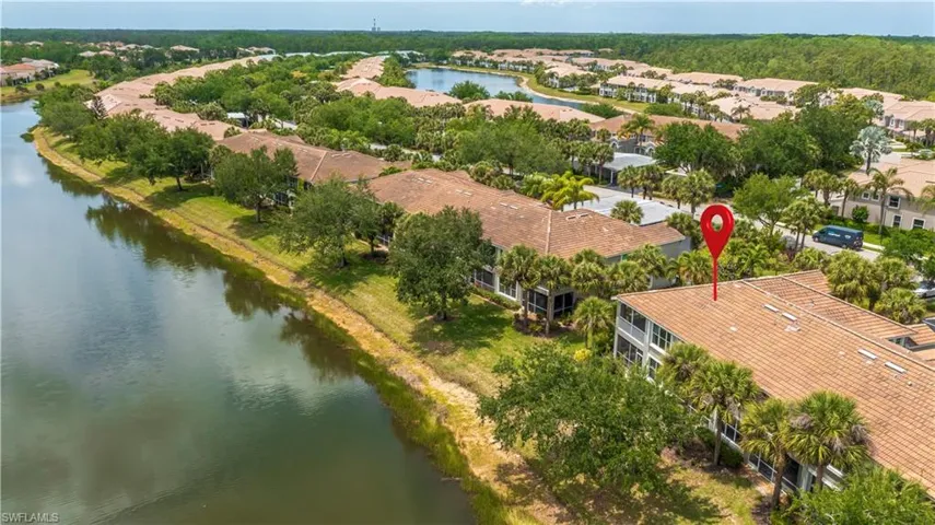 Community setting featuring waterfront buildings with tile roofs, screened balconies, and mature palm trees