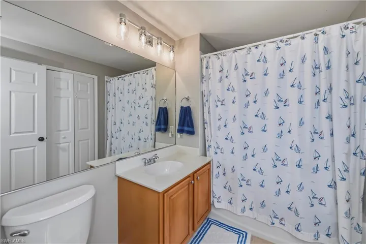 Bright bathroom featuring a single vanity with wood-finish cabinetry, a white countertop, and a chrome faucet
