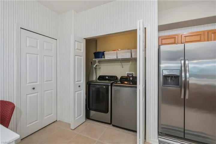 Laundry closet featuring bi-fold doors, a washer and dryer, and wire shelving