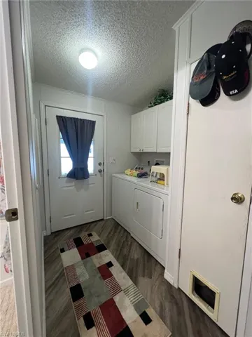 Washroom with cabinets, dark hardwood / wood-style flooring, washer and dryer, and a textured ceiling