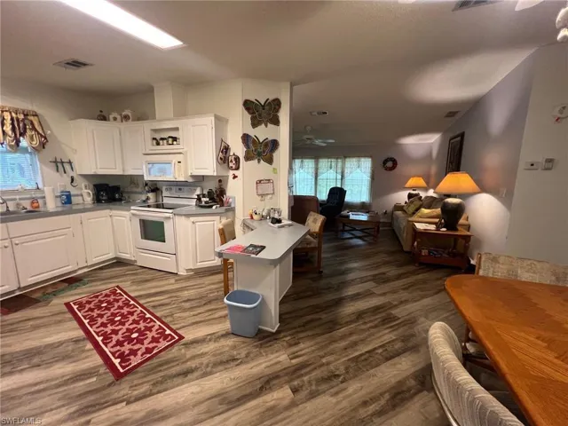 Kitchen featuring white cabinetry, ceiling fan, dark wood-type flooring, and white appliances