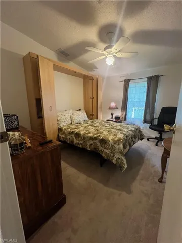 Carpeted bedroom with ceiling fan and a textured ceiling