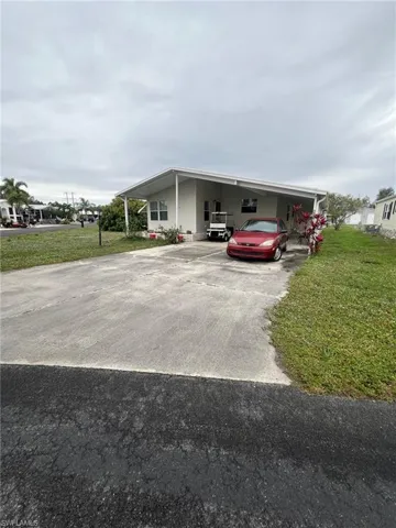 View of front of property with a front yard and a carport