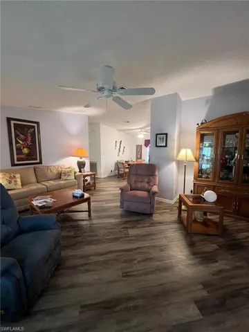 Living room featuring ceiling fan and dark wood-type flooring
