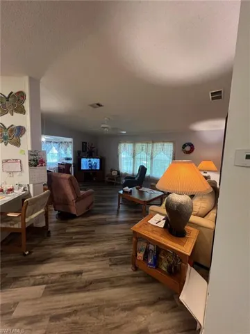 Living room featuring a textured ceiling, hardwood / wood-style flooring, and ceiling fan