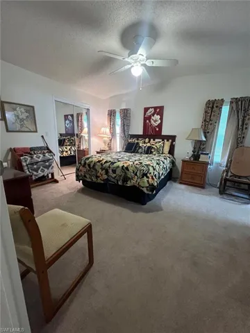 Bedroom featuring carpet flooring, ceiling fan, a closet, and a textured ceiling
