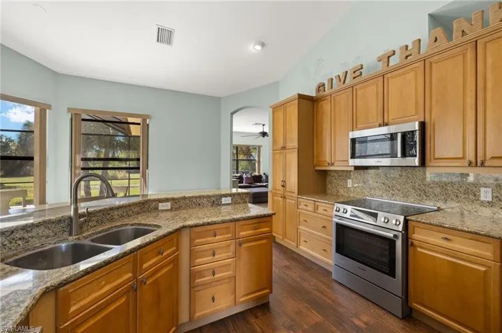 Kitchen with a healthy amount of sunlight, stainless steel appliances, light stone countertops, and sink