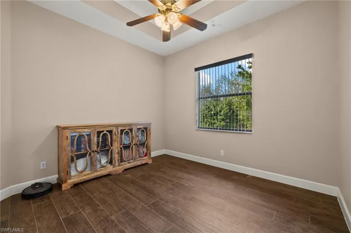 Unfurnished room featuring dark wood-type flooring and ceiling fan