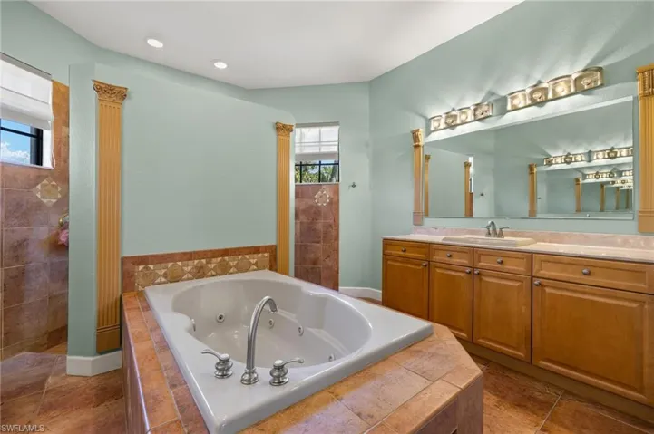 Bathroom featuring vanity, tiled tub, and tile patterned floors