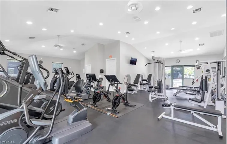 Workout area featuring a ceiling fan, visible vents, and vaulted ceiling