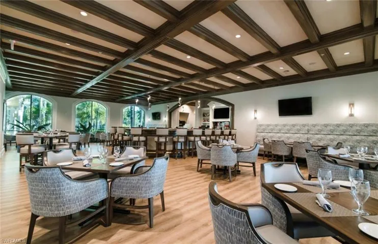 Dining space with light wood-style floors, arched walkways, and beam ceiling