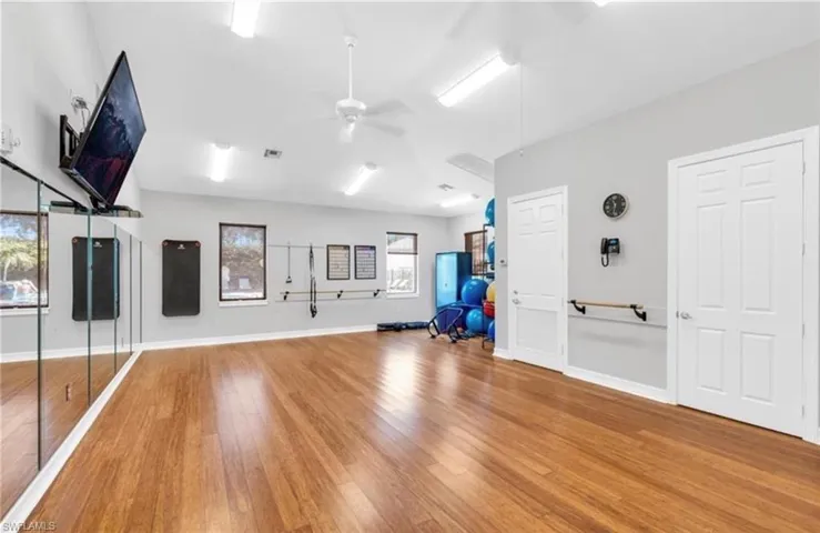 Exercise area with ceiling fan, wood finished floors, visible vents, and baseboards