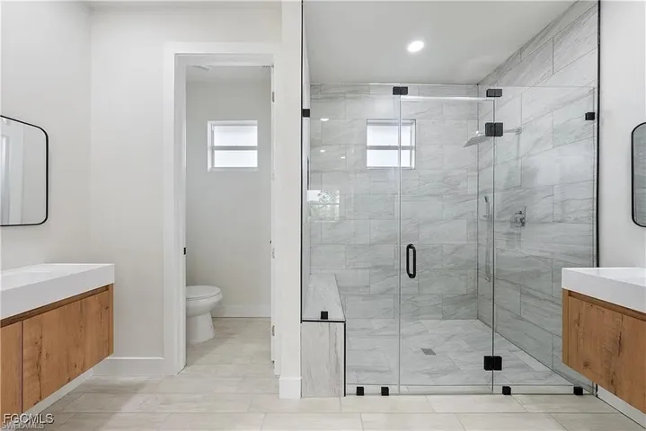 Expansive walk-in shower with glass enclosure, tiled walls, and a built-in bench