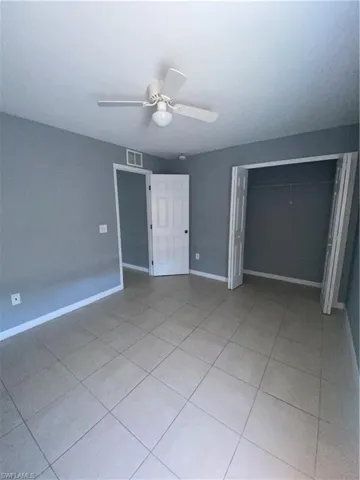 Unfurnished bedroom featuring ceiling fan, light tile patterned floors, and a closet
