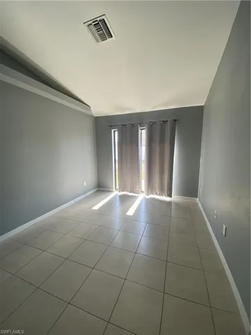 Unfurnished room featuring vaulted ceiling and light tile patterned floors
