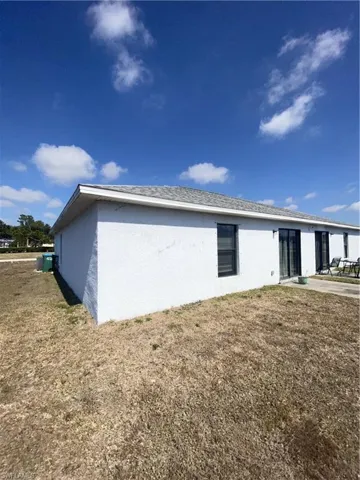 View of home's exterior with stucco siding, a lawn, and a patio area