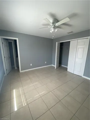 Unfurnished bedroom featuring a closet, a ceiling fan, and light tile patterned flooring